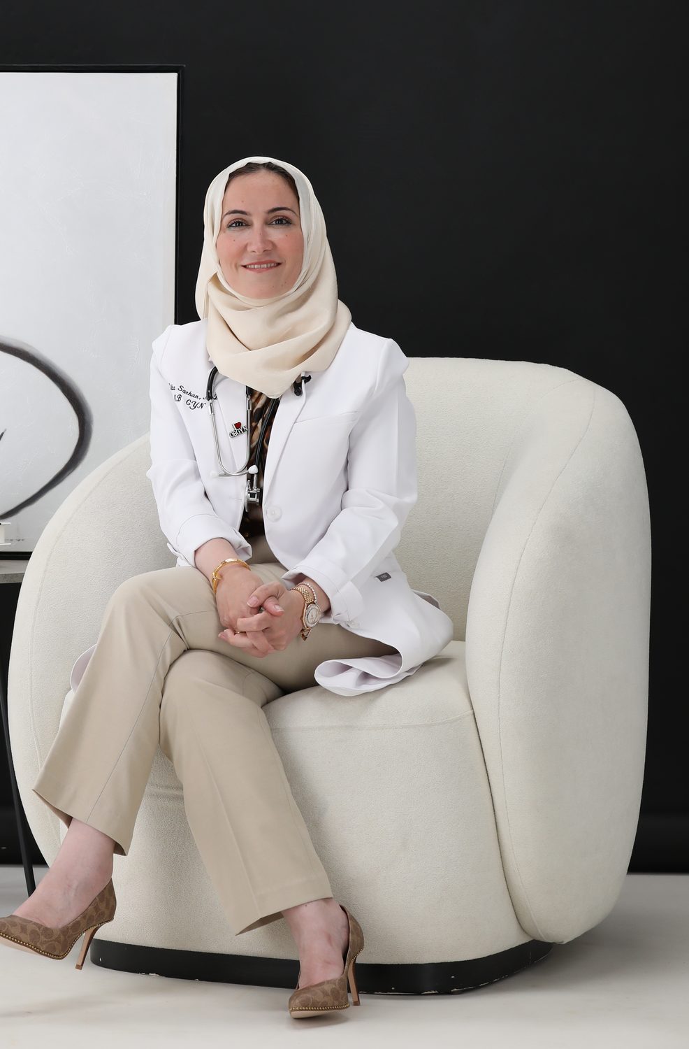 د. هبه سرحان جالسة في عيادتها بالمعطف الأبيض